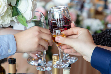 Hands of people clinking glasses with red and white wine in restaurant