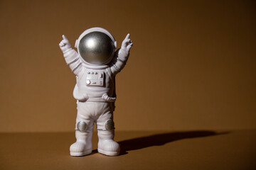 Plastic toy figure astronaut on beige neutral background Copy space. Concept of out of earth...