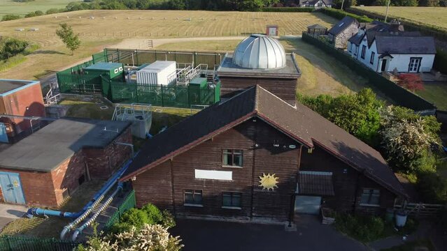 Aerial view Pex hill Leighton observatory silver dome rooftop on hilltop farmland at sunrise, tilt down rise