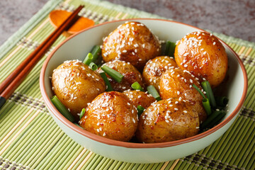 Korean Side Dish Potatoes Gamja Bokkeum or Gamja jorim in Sweet sauce Sprinkle with Sesame closeup on the bowl on the table. Horizontal