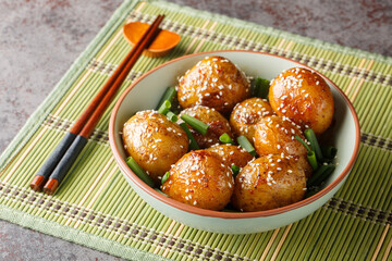 Braised new Potatoes in Sweet sauce Sprinkle with Sesame closeup on the bowl on the table. Horizontal