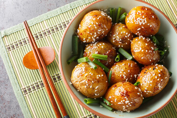 Korean Potato Side Dish Gamja Jorim braised in a sweet soy and sesame sauce closeup on the bowl on the table. Horizontal top view from above