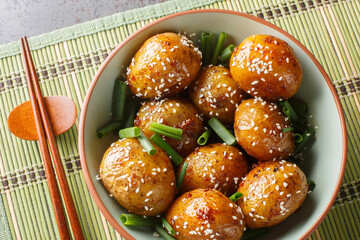 Korean Side Dish Potatoes Gamja Bokkeum or Gamja jorim in Sweet sauce Sprinkle with Sesame closeup on the bowl on the table. Horizontal top view from above