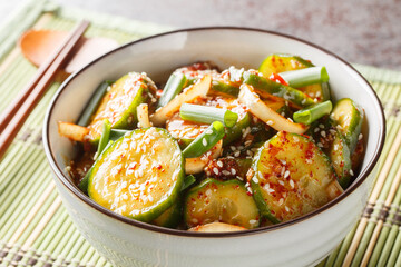 Spicy Korean cucumber salad in kimchi sauce with sesame seeds in a bowl with chopsticks on the...