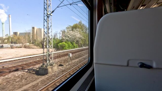 A view looking out of a train window travelling through the scenic German countryside between Berlin and Munich passing a number of platforms and stations, Germany