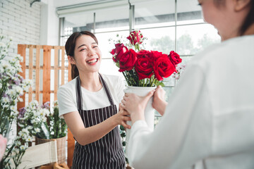 Young florist is delivering flowers beautifully arranged in a vase to a customer in a flower shop.