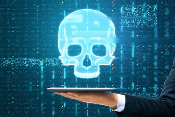 Close up of male hand holding tablet with glowing digital blue glitch skull hologram on dark background. Virus, crime and hacking concept.