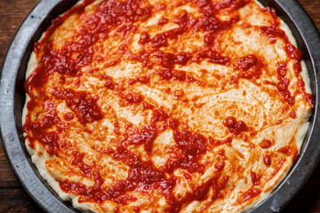 pizza cooking. Dough smeared with tomato sauce.
