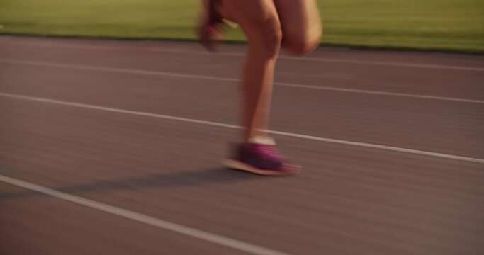 Crop female sprinter running fast on track during training