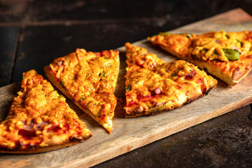 Sliced pieces of pizza on a wooden cutting board.