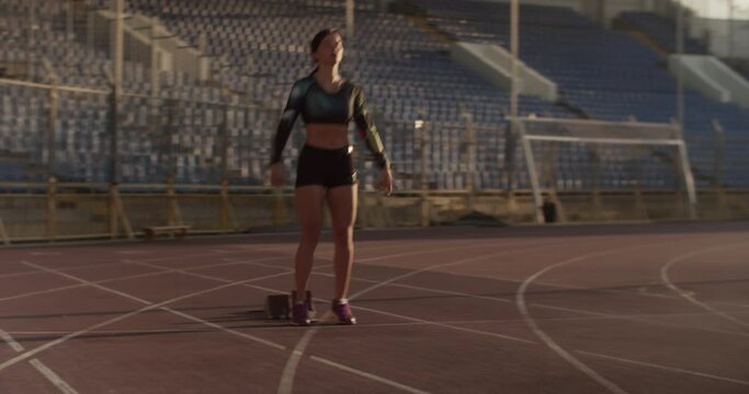 Young female sprinter preparing for run in stadium