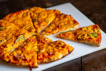 Sliced pieces of pizza on a white cutting board.