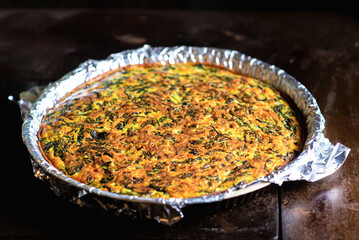 Freshly made homemade pie with spinach, cheese and egg. Vegetarian pie in shape on a dark background.