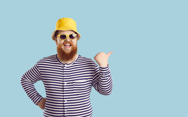 Studio portrait of funny fat ginger man in swimwear, hat and sun glasses enjoying summer holidays,...