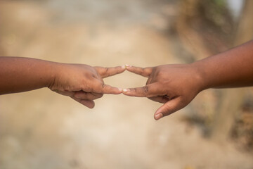A young man shows his both hand with signs of love and a background blur