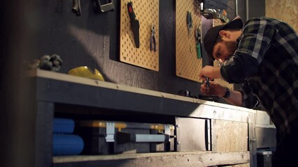 Young man by workbench diy repairing electric device