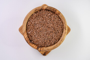 Len zwyczajny brązowy nasiona w drewnianej brązowej misce na jasnym tle