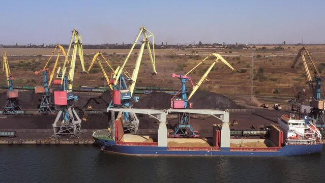 Sea port with an idle ship and cranes with coal piles. Logistic and transportration concept.