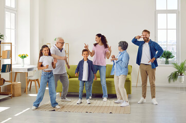 Big friendly family grandparents, parents and children dancing in living room at home. They are happy having fun spending time together on weekend. Three generations, lovely family moments concept.