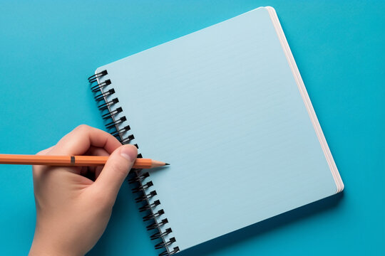 Mockup template with blank notebook and female left hand holding pen pointing at paper sheet on black background. Generative AI