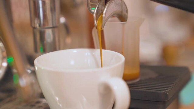 Coffee machine making espresso in white ceramic cup. Closeup, handheld