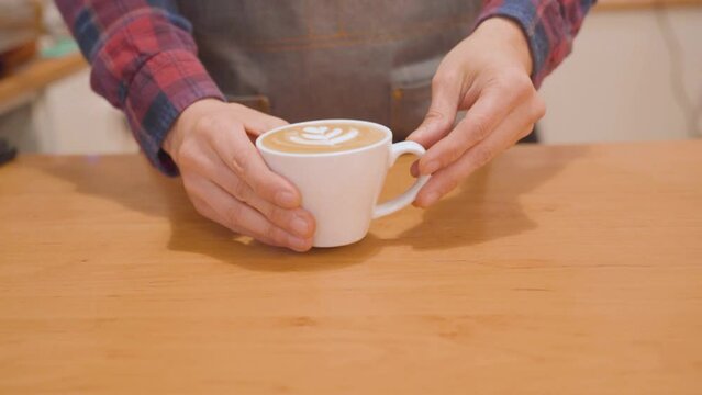 Cup of coffee with latte art. Barista serves decorated coffee. Slow motion, closeup