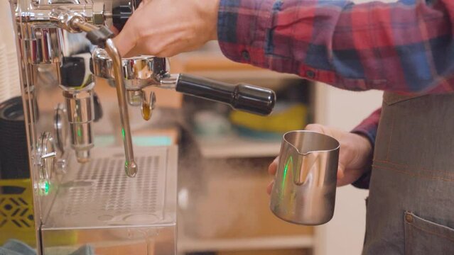Barista preparing steamed milk for cappuccino, checking temperature with hand