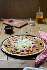 Vegetable and salami pizza on a wooden table before baking, with mozzarella cheese.  food photography .