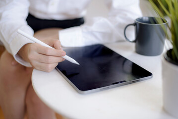close-up women holding digital tablet black screen and stylus pen has coffee cup on the table
