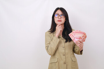 Thoughtful Civil servant woman holding Indonesian banknotes while thinking something