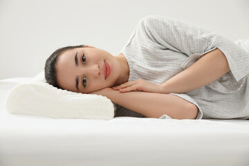 Woman lying on orthopedic memory foam pillow indoors