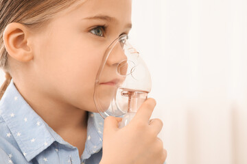 Sick little girl using nebulizer for inhalation indoors, closeup