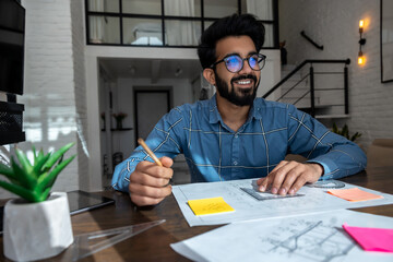 Dark-haired young man sitting at the table and preparing a project draft