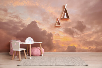 Picturesque sky with clouds as wallpaper pattern. Baby room interior with table and chairs near wall © New Africa