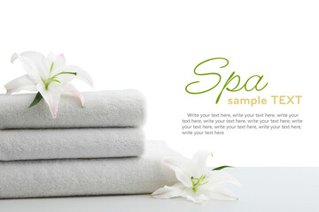 Obraz na płótnie Canvas Stack of soft towels for spa procedures and lily flowers on table against white background. Design with space for text
