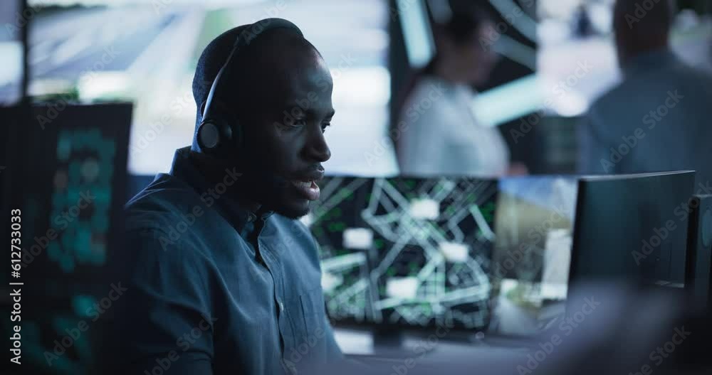 Poster African Specialist in a Dark High-Tech Monitoring Room, Concentrated on a Call and Computer Work. Black Technical Support Manager Using Headphones with Built-In Mic for Communication with Client