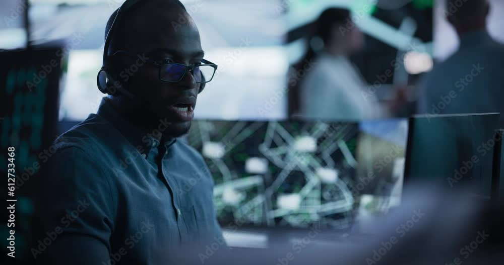 Poster Handsome Surveillance Specialist in a Modern Monitoring Room with Displays and Computers. Black Man Effectively Multitasking with Supporting Clients on a Phone Call and Computer Work