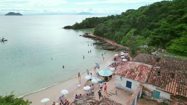 Bird's eye view of Azeda and Azedinha beaches, B&uacute;zios, Brazil. People enjoying themselves on its shore with a dirt road connecting both beaches hidden in mountains of dense vegetation.