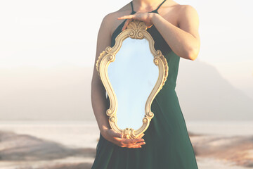 woman holding a magical mirror which reflects sunlight; abstract concept - 612734200