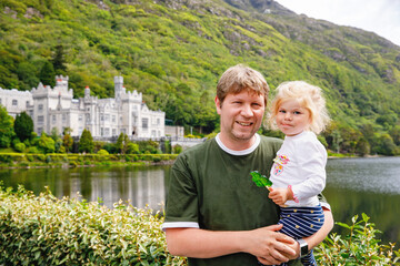 father with little daughter with Kylemore Abbey on background. Man and toddler girl. Family and...