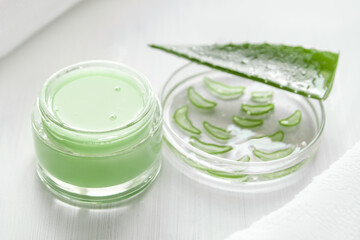 Green Aloe Vera Gel. In a jar on a light background. Petri dish with sliced aloe, green leaf