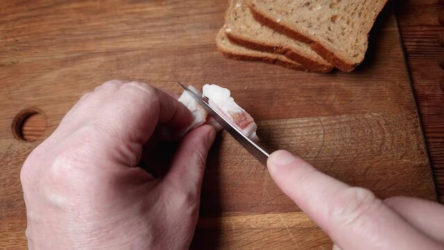 Slicing of salted pork fatback on cutting board, close-up