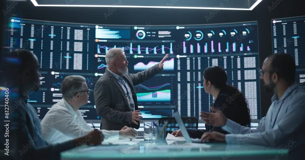 Poster Senior Team Leader is Making a Presentation on a Management Meeting in a Big Data Monitoring Company. Diverse Team of Data Scientists Discussing Graphs and Reports on Big Digital Screen in the Office