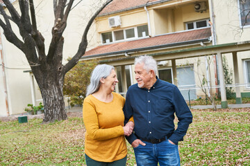 Smiling senior couple standing in garden of nursing home