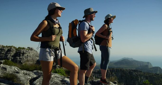 Exercise, freedom and hiking friends on a mountain happy, smile and bonding on an adventure against sky. Trekking, fitness and group of people on hill for travel, summer outdoor or nature backpacking