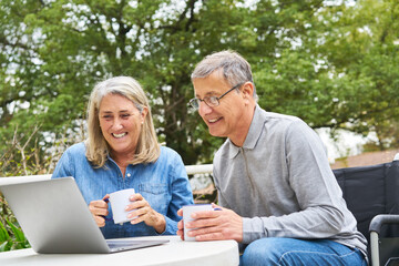 Happy senior couple discussing over laptop at table in garden