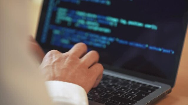 Software developer is working on creating software, typing program code on a laptop keyboard, programmer at work, hand view.