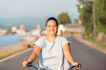 Happy smiling woman riding bicycle along the coast at summer © 24K-Production