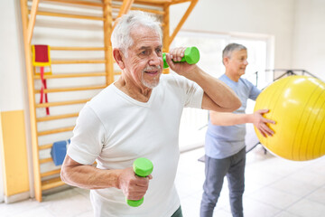 Elderly man exercising with dumbbells at rehabilitation center