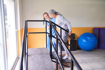 Physiotherapist assisting senior woman in climbing ramp